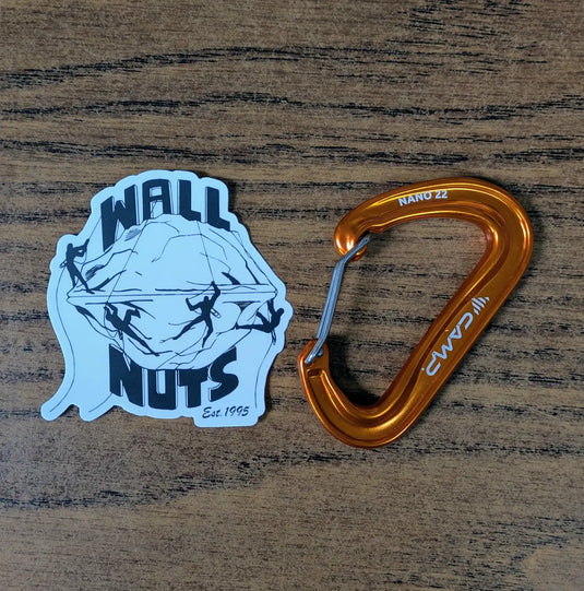 Orange carabiner and 'Wall Nuts' sticker on a wooden surface