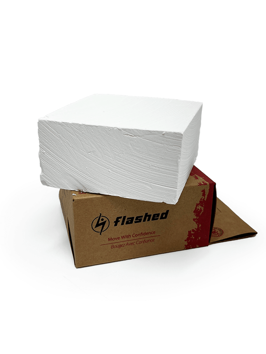 Small block of athletic chalk on top of a cardboard box on a white background